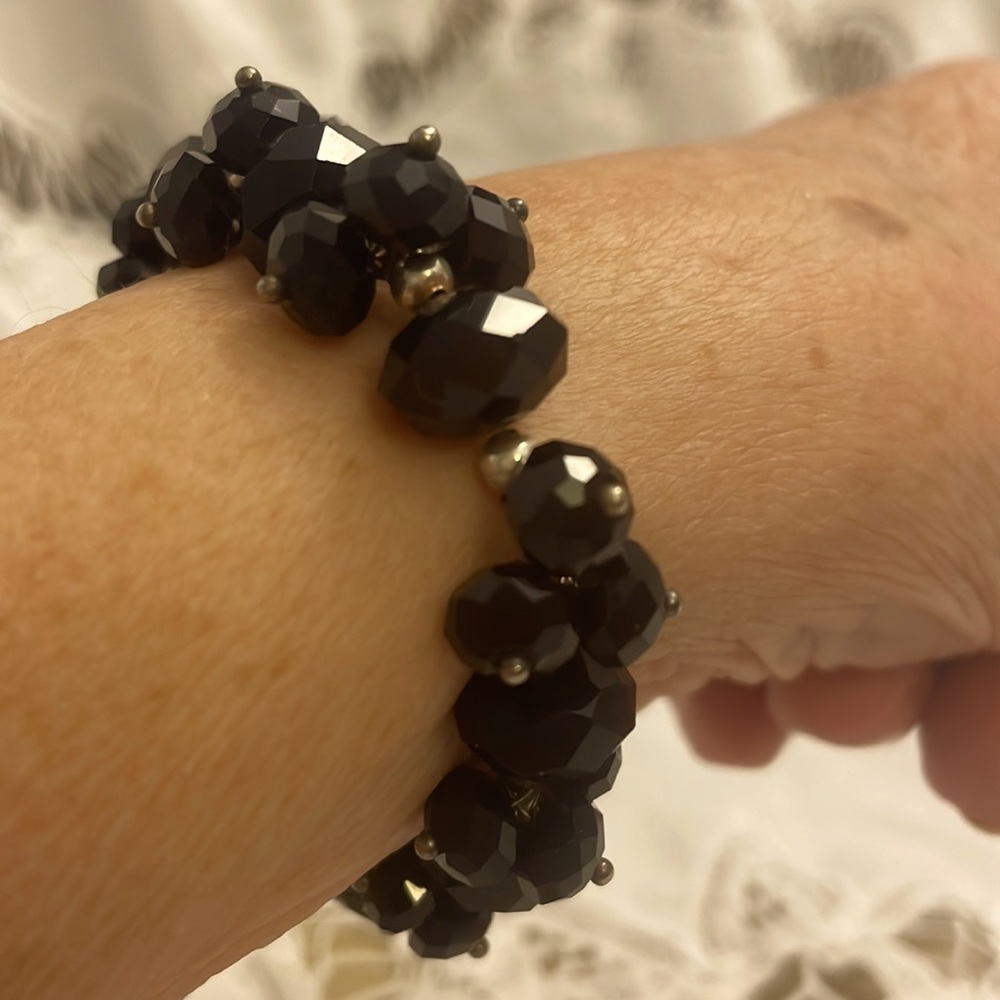 Handmade black glass bracelet embellished with gold beads. Average size stretch.